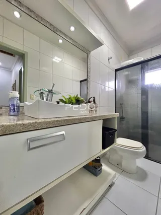 Foto de um banheiro com revestimento cerâmico branco e bancada clara.