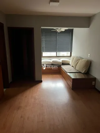 Interior de uma sala com piso de madeira e janela.