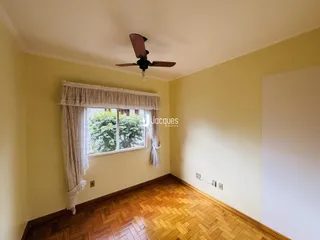 Esta é uma foto de uma sala com piso de madeira e cortinas brancas.