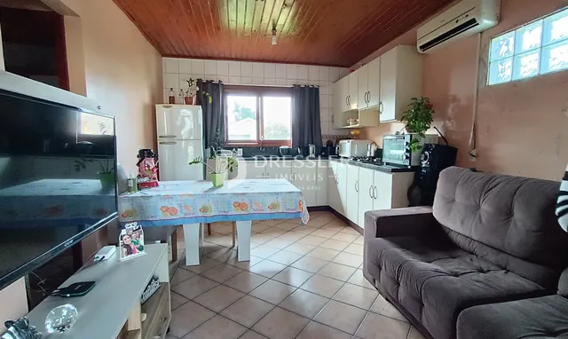 Interior de uma sala de estar com cozinha em um imóvel no Brasil.
