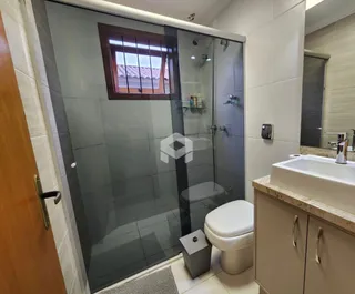 Foto de um banheiro com box de vidro e louças sanitárias.