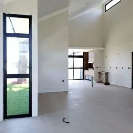 Ambiente interno amplo com paredes brancas e porta de vidro voltada para o exterior.