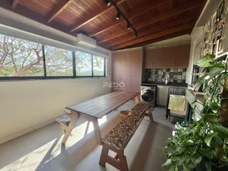 Sala de jantar com grande janela e teto de madeira em imóvel no Brasil.