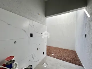 Vista de um corredor interno com paredes brancas e piso de concreto.