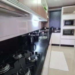 Vista de uma cozinha com bancadas escuras e eletrodomésticos modernos.