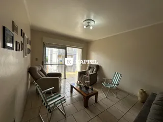Sala de estar com sofá e cadeiras voltadas para a porta de vidro.