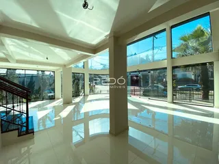 Ambiente interno amplo com piso de cerâmica e grandes janelas de vidro.