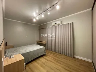 Foto de um quarto com cama e piso de madeira clara.