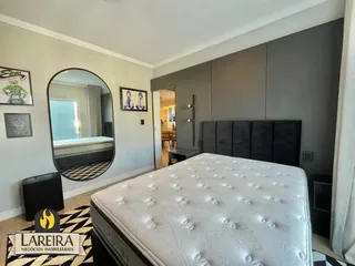 Quarto com cama grande e espelho em ambiente claro.