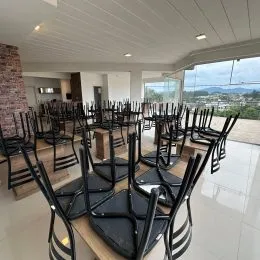 Foto de um ambiente interno com mesas e cadeiras dispostas.