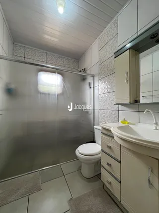 Foto de um banheiro com revestimento cerâmico e box de vidro.