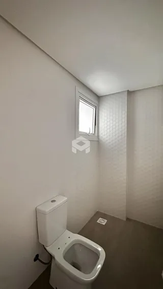 Foto de um banheiro interno com parede branca e vaso sanitário.