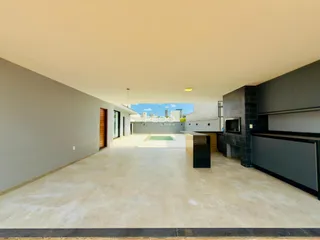 Vista ampla de um espaço interno moderno com piso claro e cozinha escura.
