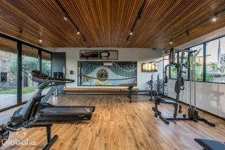 Imagem de uma área comum com piso de madeira e equipamentos de ginástica.