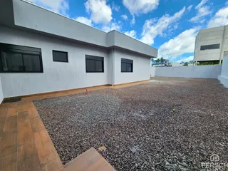 Fachada externa de uma residência branca com área de paisagismo em cascalho.