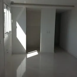 Hall de entrada com paredes brancas e luz solar intensa.