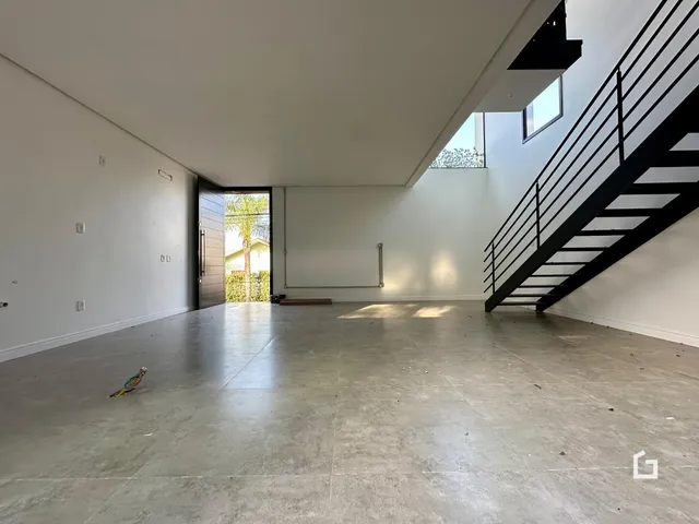 Espaço interno amplo com piso de concreto e escadaria preta.