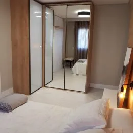 Quarto com cama e armário de espelho em um imóvel.