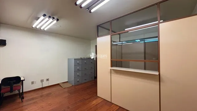 Ambiente interno com piso de madeira e divisória de vidro.
