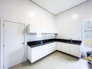 Cozinha com armários brancos e bancada preta em um imóvel.