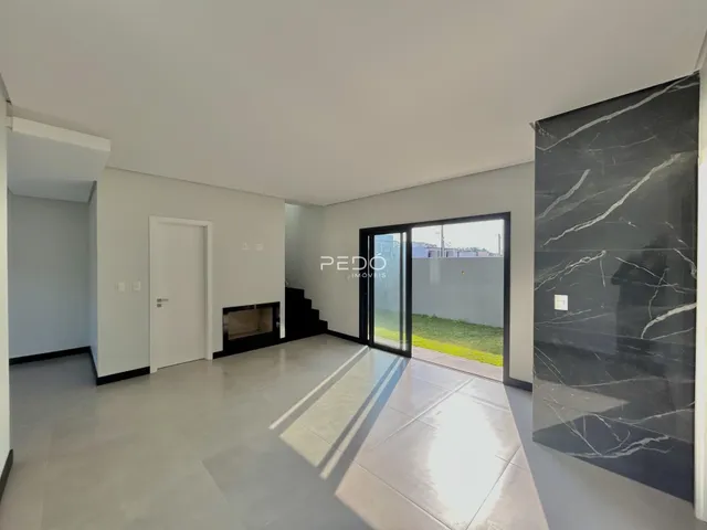 Sala de estar com piso claro e parede de mármore escura.