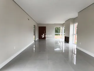 Interior de uma sala ampla com piso reflexivo e paredes claras.