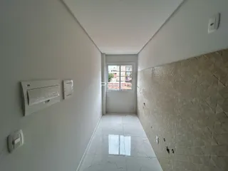 Corredor interno de uma residência com paredes brancas e piso de cerâmica clara.