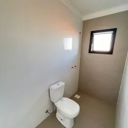 Vista interna de um banheiro com parede branca e janela.