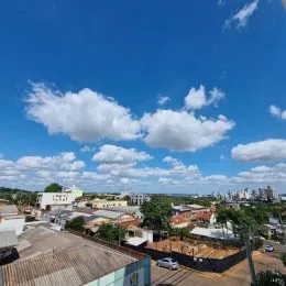 Vista aérea de um bairro residencial em Lajeado, Brasil, mostrando telhados e vegetação sob um céu azul.