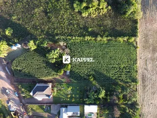 Vista aérea mostrando uma propriedade rural com plantações verdes e estruturas residenciais.