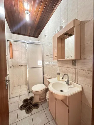 Banheiro com revestimento de azulejos e louças brancas.