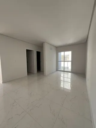 Sala ampla com piso de porcelanato branco e paredes brancas.