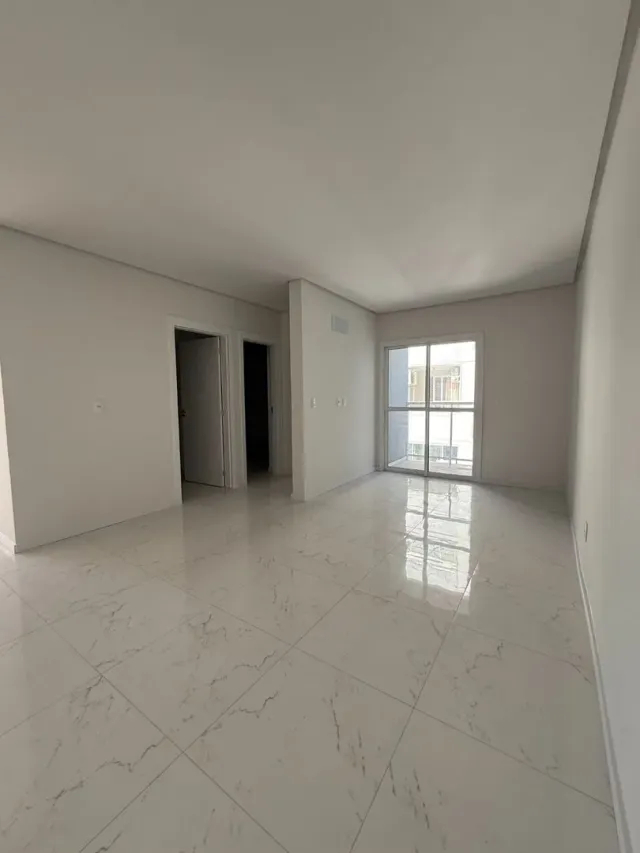 Sala ampla com piso de porcelanato branco e paredes brancas.