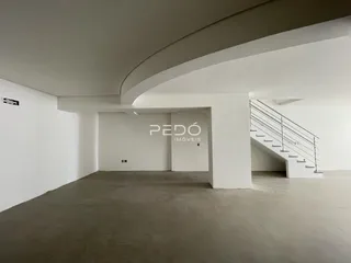 Interior de um espaço amplo com paredes brancas e piso de concreto.