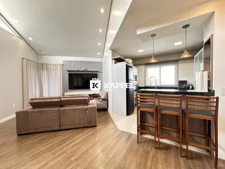 Sala de estar moderna com sofá e área de cozinha integrada em um ambiente claro.
