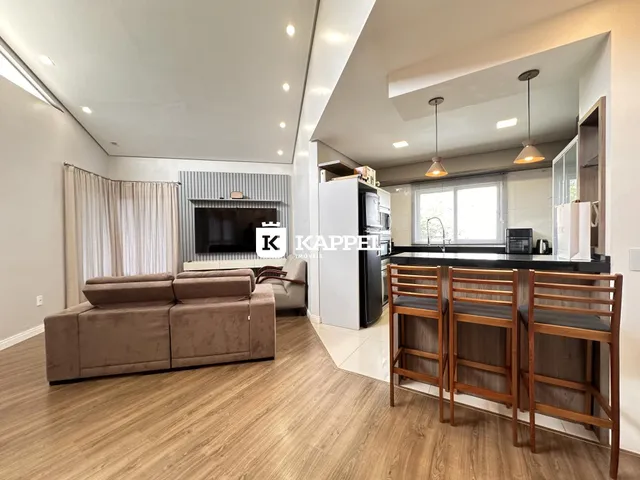 Sala de estar moderna com sofá e área de cozinha integrada em um ambiente claro.
