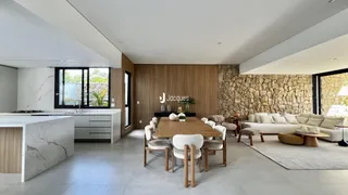 Ambiente moderno de sala de estar e jantar com paredes de pedra e piso de madeira.