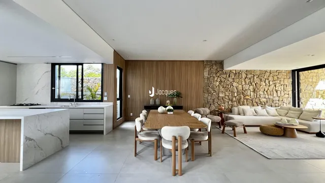 Ambiente moderno de sala de estar e jantar com paredes de pedra e piso de madeira.