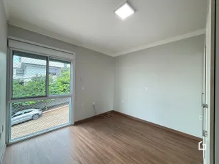 Ambiente interno de uma sala com piso de madeira e grande janela.