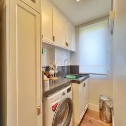 Foto de uma cozinha com armários brancos e máquina de lavar roupa.