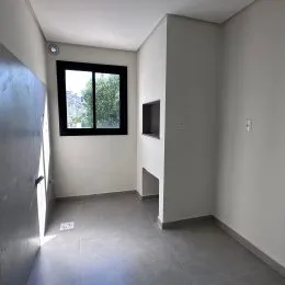 Hall de entrada com parede branca e janela visível.
