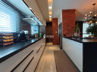 Cozinha moderna com armários brancos e bancadas escuras.
