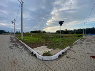 Vista externa de uma área de terreno com pavimento e vegetação rasteira.