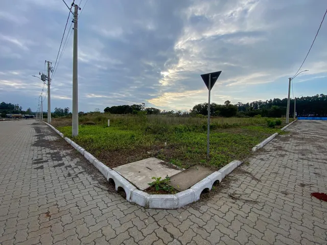 Vista externa de uma área de terreno com pavimento e vegetação rasteira.