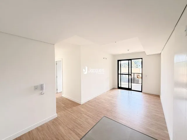 A sala apresenta paredes brancas e piso de madeira clara.