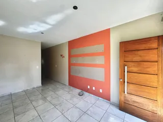 Foto de um corredor interno com piso de cerâmica e uma parede de destaque laranja.