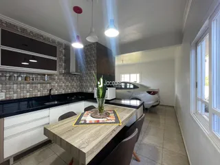 Cozinha com armários brancos e bancada escura.