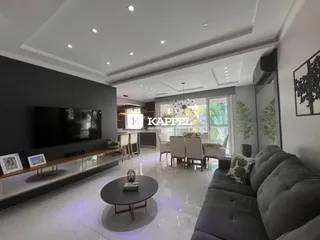 Sala de estar moderna com sofá cinza e televisão na parede, com vista para o exterior.