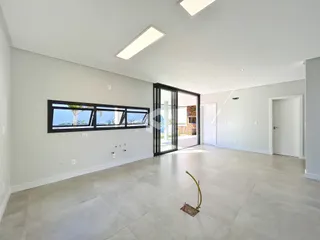 Ambiente interno amplo com grandes janelas e piso claro.