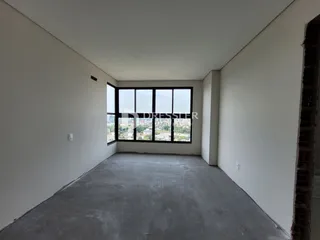 Ambiente interno vazio com grande janela de vista para a cidade.